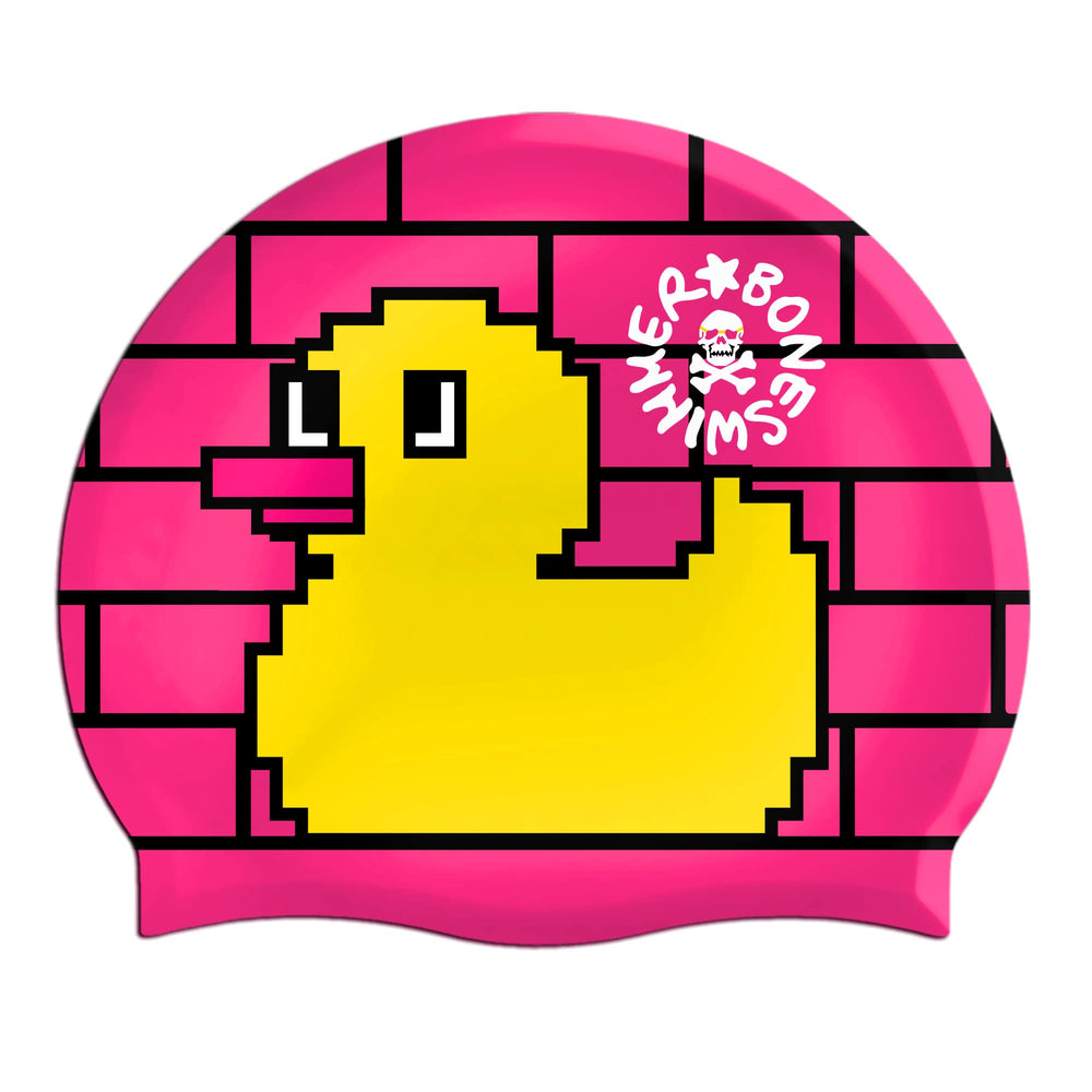 una paperella gialla in stile pixel si Cuffia da piscina in silicone spessorato, modello CBONE Boneswimmer con base colore fucsia e grafica con una paprella pixelosa si staglia sul fondo di un muro di piastrelle fucsia